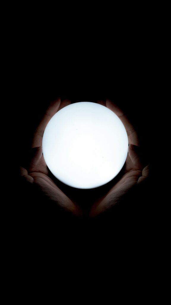 Hands holding a glowing white orb against a dark background.