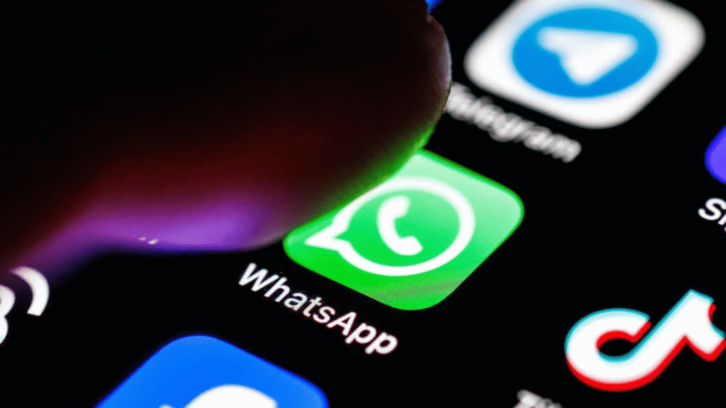 Close-up of a finger tapping the WhatsApp icon on a smartphone screen, with Telegram, Instagram, and TikTok app icons visible nearby.